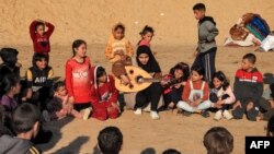 Ruaa Hassouna plays music for Palestinian children on her Oud (Ud, or oriental lute) in Rafah in the southern Gaza Strip on December 18, 2023.