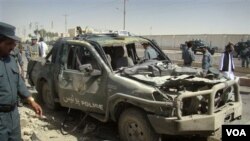 Polisi Afghanistan memeriksa sebuah mobil polisi yang rusak dalam serangan bunuh diri di Lashkar Gah, provinsi Helmand (27/9).