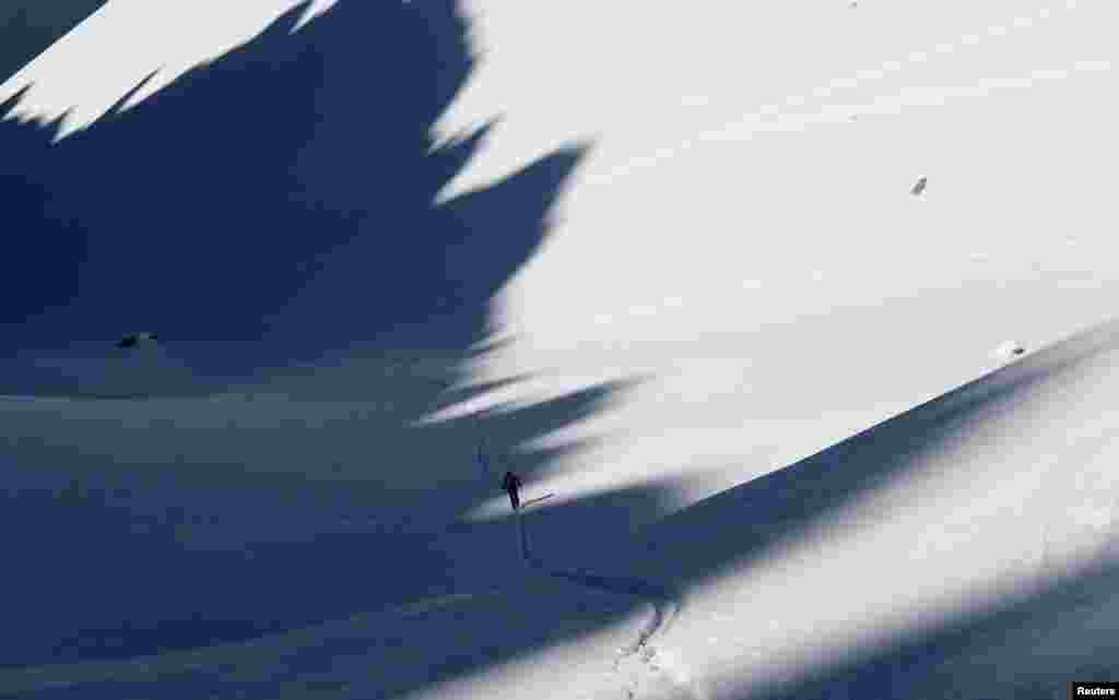 A ski tourer walks through the shadows cast by the mountains near Garmisch-Partenkirchen, Germany.