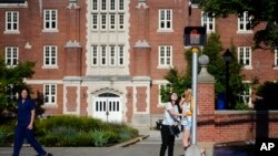 FILE - In this Sept. 18, 2015, photo, a University of Connecticut student pushes a button at a crosswalk outside a dormitory, in Storrs, Conn. 