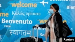 FILE - A traveler wears a face mask as she arrives at John F. Kennedy International Airport in New York City, March 20, 2020. 