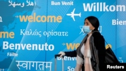 FILE - A traveler wears a face mask as she arrives at John F. Kennedy International Airport in New York City, March 20, 2020. 