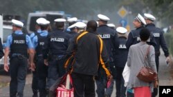 Sejumlah warga meninggalkan apartemennya dan berjalan di belakang polisi selama evakuasi lebih dari 60.000 orang di Frankfurt, Jerman, Minggu, 3 September 2017.