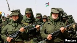 FILE - Sahrawi women soldiers carry their weapons during a parade at the Awserd refugee camp in Tindouf, Algeria, Feb. 27, 2021.