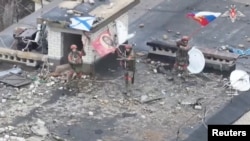 A drone view shows Russian service members waving flags on the roof of a building in the settlement of Velyka Novosilka in the Donetsk region, a Russian-controlled part of Ukraine, in this still image from video released Jan. 26, 2025. Russian Defense Ministry/Handout