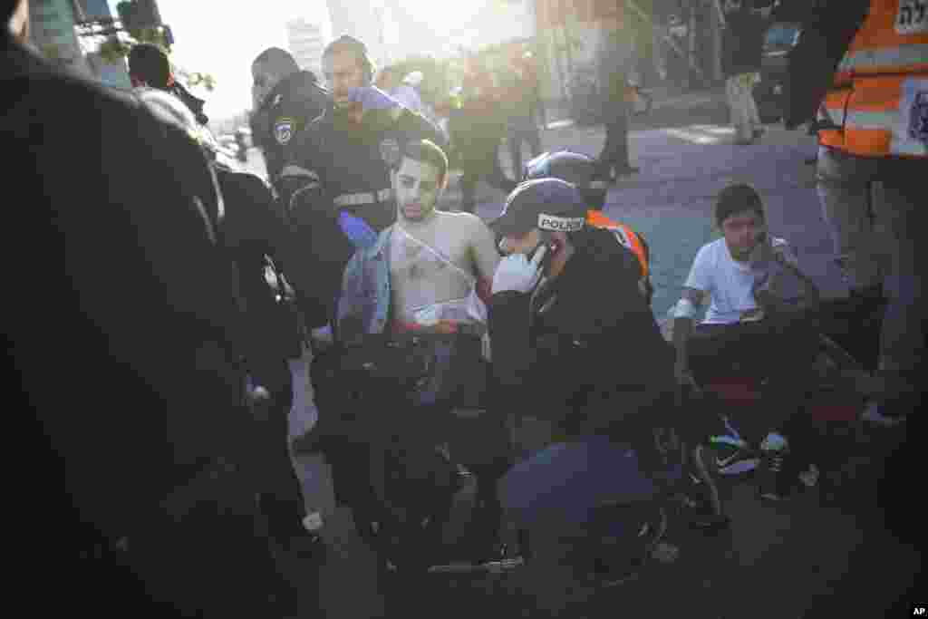 An Israeli police officer and paramedics treat an injured man at the scene of a stabbing in Tel Aviv, Jan. 21, 2015.
