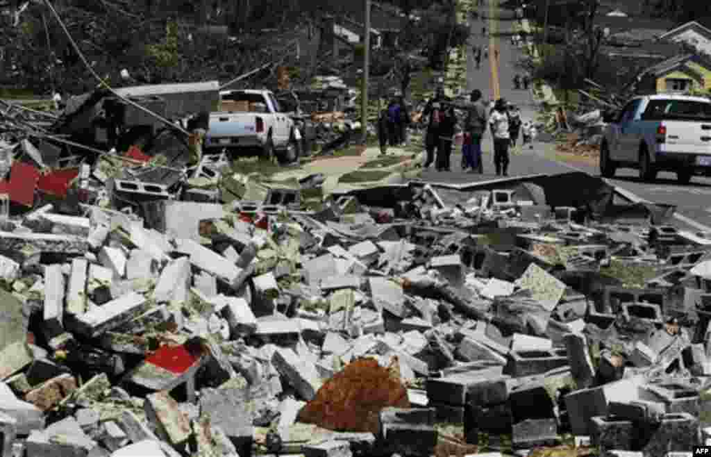 People walk along the streets in the Alberta City neighborhood Thursday April 28, 2011, after a tornado struck Tuscaloosa, Ala. the day before. Massive tornadoes tore a town-flattening streak across the South, killing at least 269 people in six states and