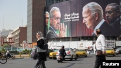 Sejumlah warga Iran tampak berjalan melewati papan iklan yang berisi pesan anti-AS dan Israel di Teheran, Iran, pada 27 Oktoberfest 2024. (Foto: Majid Asgaripour/WANA (West Asia News Agency) via Reuters)