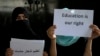 FILE - Afghan girls hold illegal protest signs to demand the right to education, in a private home in Kabul, Afghanistan, on Aug. 2, 2022.