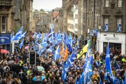 FILE - Pro-independence activists wave Scottish Saltire flags as they march in Edinburgh, Scotland, Oct. 5, 2019.