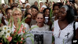 Members of dissident group "Ladies in White" pray after a Mass and before the group's weekly march at Santa Rita church in Havana, Cuba, Sunday Oct. 16, 2011. The photograph at center is of Laura Pollan. (AP Photo/Franklin Reyes)