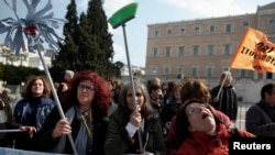 Cleaning ladies in the public sector shout slogans during a rally outside the parliament in Athens, March 12, 2014.