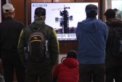 People watch a TV screen showing a file image of the North Korean long-range rocket at a launch pad during a news program at the Seoul Railway Station in Seoul, South Korea, Monday, Dec. 9, 2019.