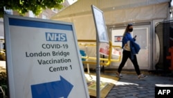 FILE - Signs are posted at the entrance to the London Bridge Vaccination Centre as people leave after receiving doses of a COVID-19 vaccine in London, Britain, Aug. 9, 2021. 