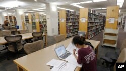 FILE - A student works in the library at a college in Richmond, Va. 