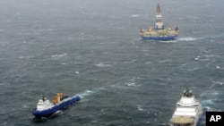 In this photo provided by the United States Coast Guard, the tugs Aiviq and Nanuq tow the mobile drilling unit Kulluk while a Coast Guard helicopter from Air Station Kodiak transports crew members on Dec. 29, 2012, 80 miles southwest of Kodiak City, Alaska.