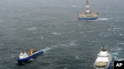 In this photo provided by the United States Coast Guard, the tugs Aiviq and Nanuq tow the mobile drilling unit Kulluk while a Coast Guard helicopter from Air Station Kodiak transports crew members on Saturday, Dec. 29, 2012, 80 miles southwest of Kodiak C