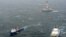In this photo provided by the United States Coast Guard, the tugs Aiviq and Nanuq tow the mobile drilling unit Kulluk while a Coast Guard helicopter from Air Station Kodiak transports crew members on Dec. 29, 2012, 80 miles southwest of Kodiak City, Alaska.