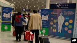 Los viajeros pasan por un punto de control de salud antes de ingresar a inmigración en el aeropuerto internacional de Beijing. No se puede descartar la posibilidad de que un nuevo virus en el centro de China se propague entre los humanos.