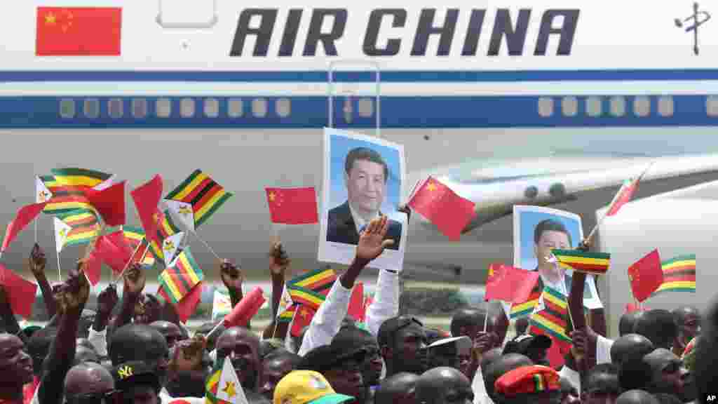 Zimbabweans wave flags while welcoming Chinese President Xi Jinping in Harare, Zimbabwe, Tuesday, Dec. 1, 2015. Jinping is in Zimbabwe for a two day State visit during which he is set to sign some bilateral agreements aimed at strengthening relationships between the two countries. 