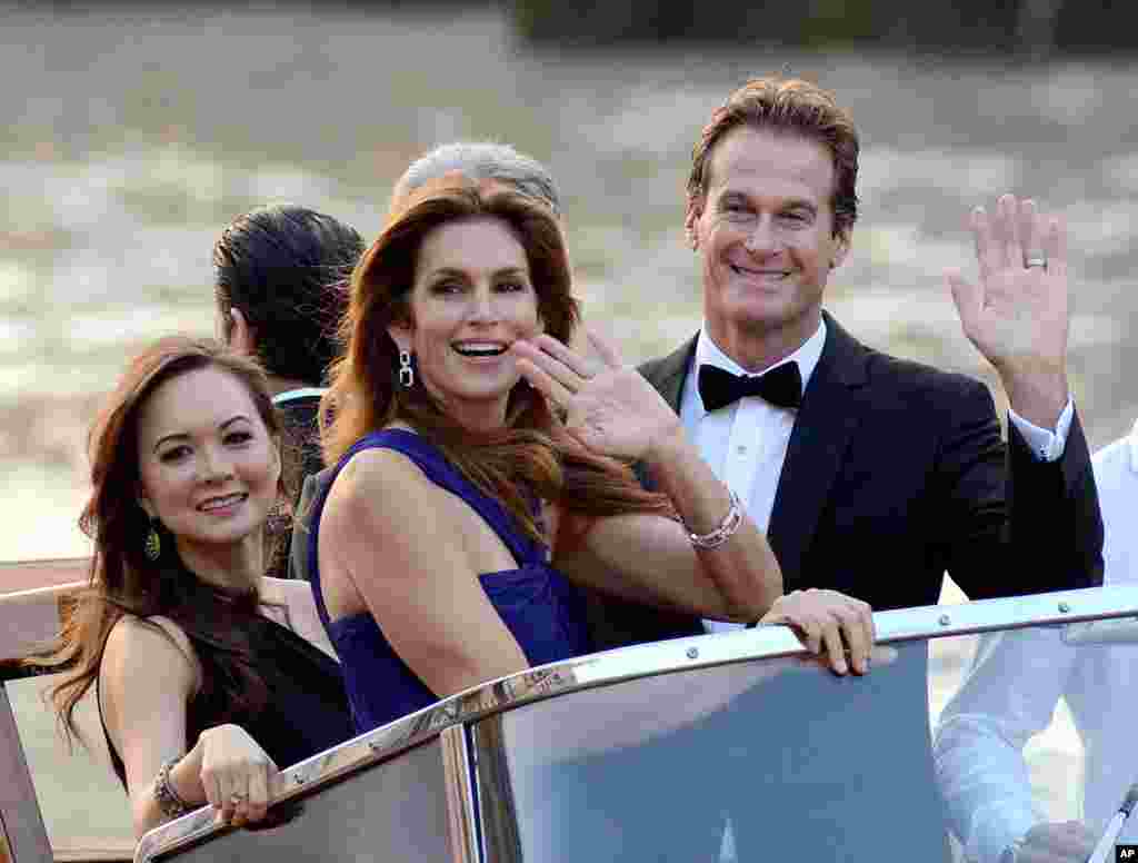Cindy Crawford and Rande Gerber wave from a boat as they go to George Clooney's wedding with Amal Alamuddin, in Venice, Sept. 27, 2014. 