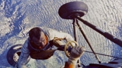 Alan Shepard being lifted to a helicopter from his space capsule after it landed in the Atlantic ocean following his suborbital flight