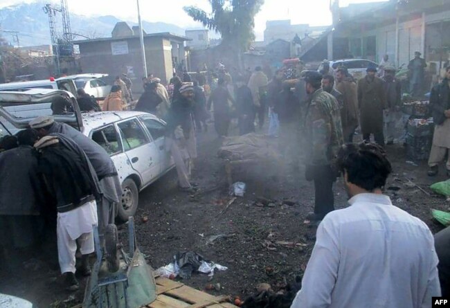 Pakistani security officals and local residents are seen gathered at the site of a bomb explosion at a market in Parachinar city, the capital of Kurram tribal district on the Afghan border on Jan. 21, 2017.