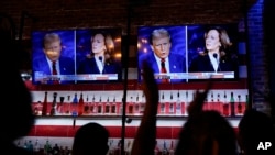 Viewers cheer as they watch a debate between Democratic presidential nominee Vice President Kamala Harris and Republican presidential nominee former President Donald Trump at the Angry Elephant Bar and Grill, Sept. 10, 2024, in San Antonio.