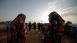 FILE - Survivors of sexual violence, who fled the conflict in El Geneina, West Darfur, walk together outside makeshift shelters for refugees in Adre, Chad, August 1, 2023. 