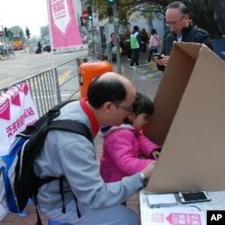 香港市民陳先生(左)帶同女兒在泛民初選投票站投票