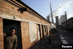 FILE - A migrant worker steps out of his living quarters in an area next to a coal power plant in Beijing.