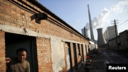 FILE - A migrant worker steps out of his living quarters in an area next to a coal power plant in Beijing.