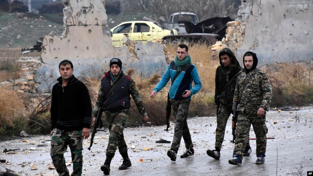 This photo released by the Syrian official news agency SANA, shows Syrian troops and pro-government gunmen marching through the streets of east Aleppo, Syria, Dec. 13, 2016. 