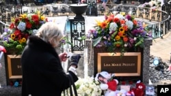 Un visitante se detiene a tomar una foto en la tumba de Lisa Marie Presley el 22 de enero de 2023 en Memphis, Tennesee, donde también está enterrado el padre de la cantante, Elvis Presley. 