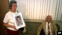 FILE - In this Aug. 9, 2001 file photo, former Guatemalan head of state, Army Gen. Oscar Humberto Mejia Victores, waits to testify as Maria Emilia Garcia, left, holds the photo of her son, union leader Fernando Garcia, at a tribunal in Guatemala City. 