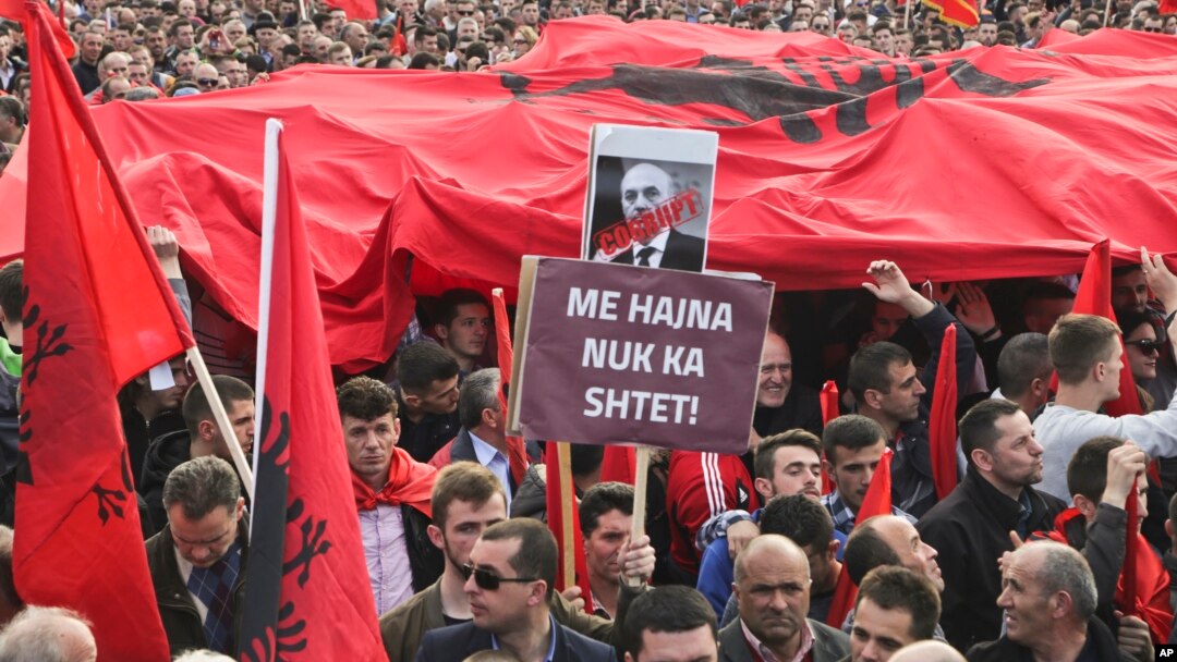 Kosovo opposition supporters wave Albanian flags during an anti-government rally in Kosovo's capital Pristina, Feb. 17, 2016. The banner in Albanian reads "Corrupt - with thieves there is no country."