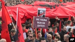 Kosovo opposition supporters wave Albanian flags during an anti-government rally in Kosovo's capital Pristina, Feb. 17, 2016. The banner in Albanian reads "Corrupt - with thieves there is no country."