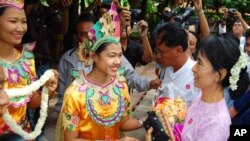 Burmese democracy icon Aung San Suu Kyi (R) receives flowers as she arrives at Bagan Hotel in Bagan, Burma, July 4, 2011