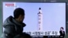 在首尔火车站，一名男子正在观看电视节目，节目显示朝鲜《劳动新闻报》刊登的一张有关朝鲜北极星-2号导弹发射的图片(2017年2月13日)