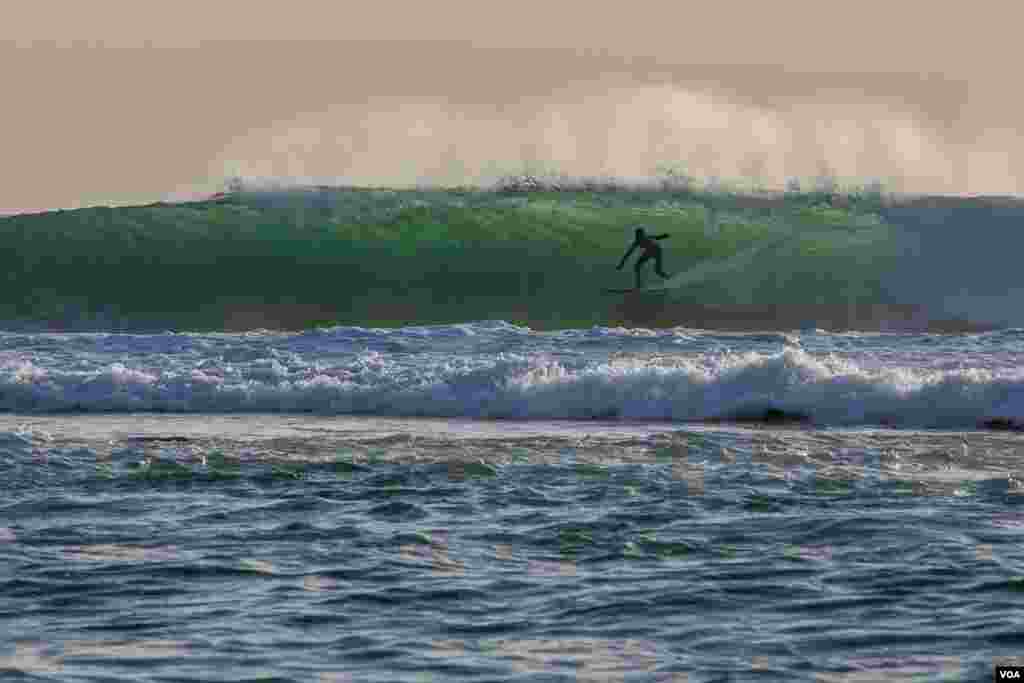 A man surfs in waters off Senegal&#39;s capital Dakar. (Annika Hammerschlag/VOA)