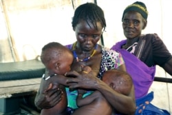 FILE - Elizabeth Girosdh breastfeeds her eight-month old twins in a health clinic in Pibor, South Sudan.