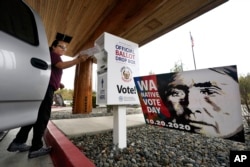 FILE - Lummi Nation tribal member Karen Scott drops her completed ballot into a ballot drop box on Oct. 19, 2020, on the Lummi Reservation, near Bellingham, Wash. Native Americans have long faced barriers to voting.