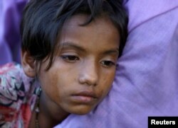 An exhausted Rohingya refugee girl leans on a family member after crossing the Bangladesh-Myanmar border while being detained by the Border Guard Bangladesh near Inani beach in Cox's Bazar, Bangladesh, Nov. 7, 2017.