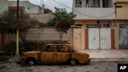 Un automóvil dañado permanece en una calle de un barrio recientemente liberado por fuerzas de seguridad iraquíes de militantes islámicos en el oeste de Mosul, Irak, el sábado 18 de marzo de 2017.