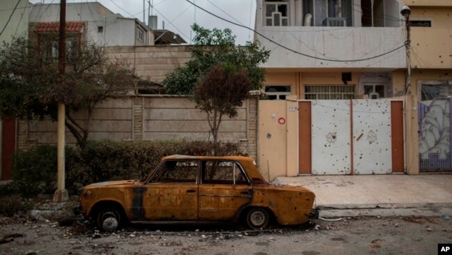 Un automóvil dañado permanece en una calle de un barrio recientemente liberado por fuerzas de seguridad iraquíes de militantes islámicos en el oeste de Mosul, Irak, el sábado 18 de marzo de 2017.