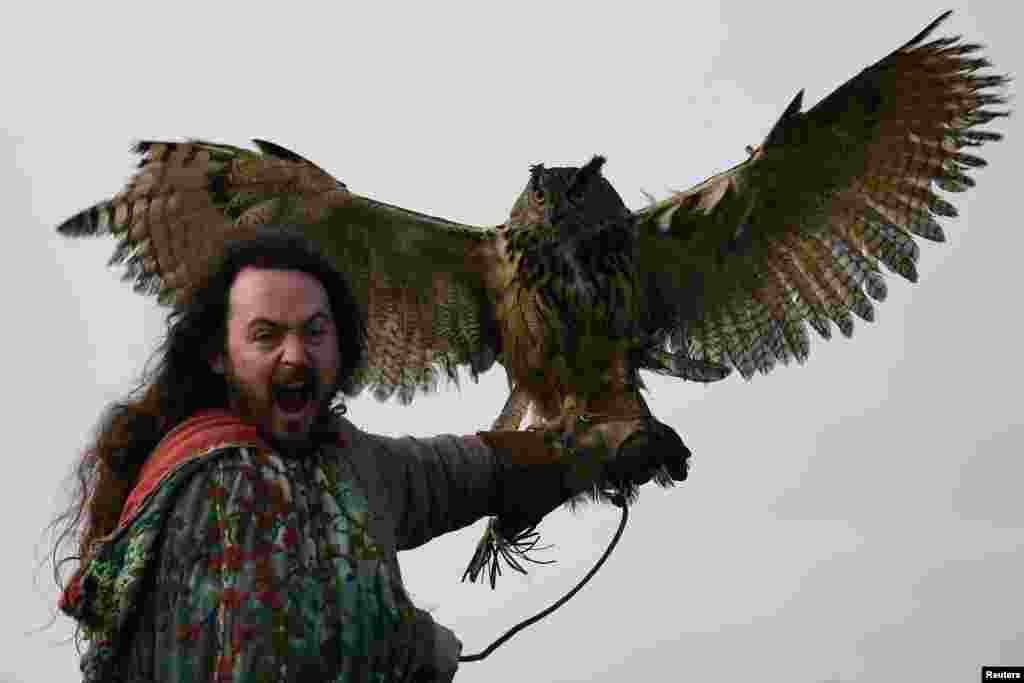 Druid Malachy, played by Ciaron Davies, reacts with a European eagle-owl named &#39;Cracker&#39; during the re-enactment of the first landing of Saint Patrick in Ireland at Inch Abbey in Downpatrick, Northern Ireland, March 11, 2018.
