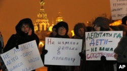 Opposition activists hold posters reading "Do not involve children in politics" and "Lawmakers, children are not your ownership" during a protest against a bill banning U.S. adoptions of Russian children in St. Petersburg, Russia, December 26, 2012.