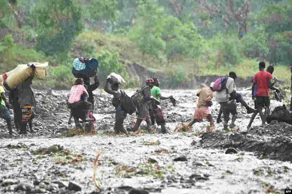 People cross the river La Digue in Petit Goave where the bridge collapsed during the rains of the Hurricane Matthew, southwest of Port-au-Prince, Haiti, Oct. 5, 2016. Haiti and the eastern tip of Cuba -- blasted by Matthew -- began the messy and probably grim task of assessing the storm's toll.
