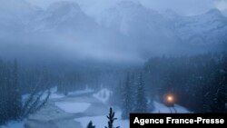 FILE - A Canadian Pacific railway locomotive pulls train cars with shipping containers east along a rail line past Morant's Curve near Lake Louise in Banff National Park, Alberta, Canada on November 29, 2021.