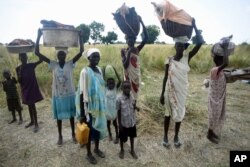 FILE - Women stand with their children and belongings in rebel held Bauw village in Koch county of South Sudan's Unity state, Sept. 25, 2015. The army and its allied militias raped and murdered civilians and burned villages in that campaign, according to the U.N.